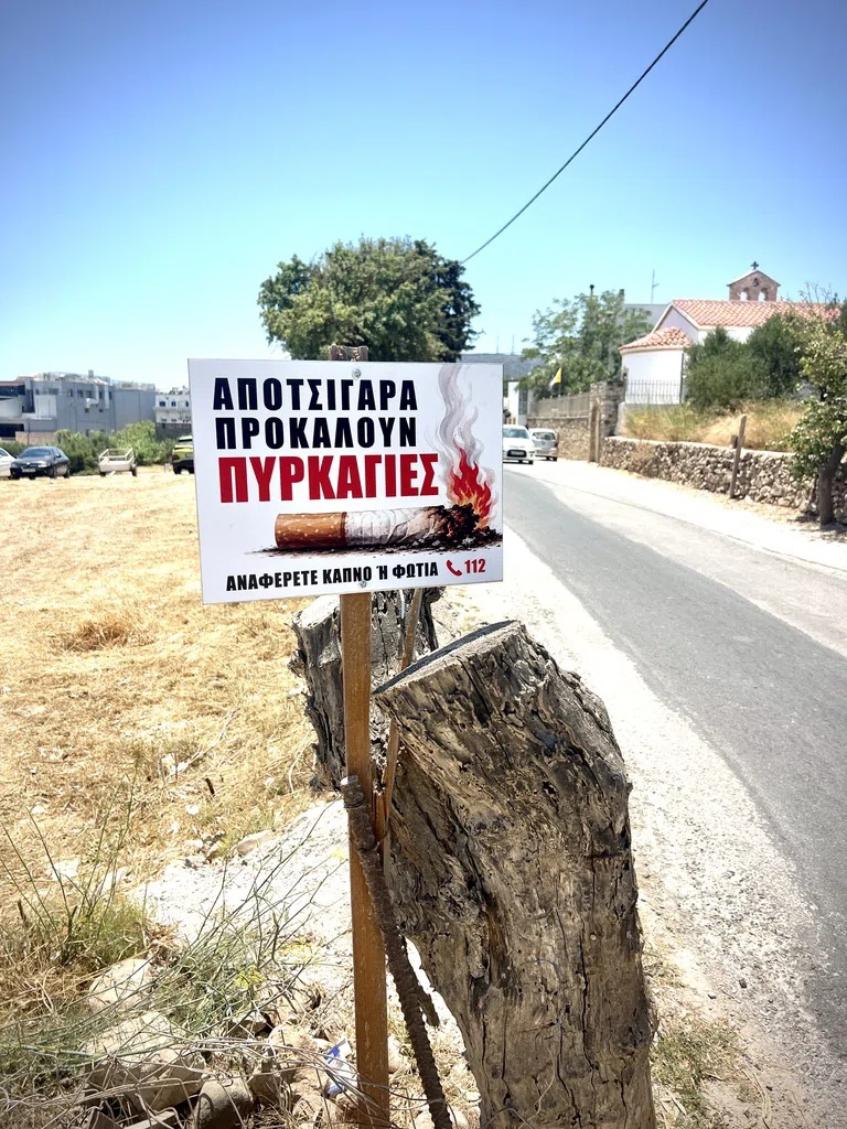 A Greek cigarette-butt fire warning beside a road